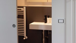 A bathroom with a white sink, black faucet, and a white towel rack.