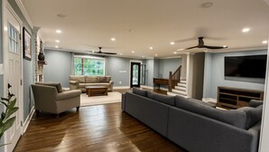 Un salón amplio con suelo de madera, un sofá modular gris, un sillón color beige y una mesa de centro.