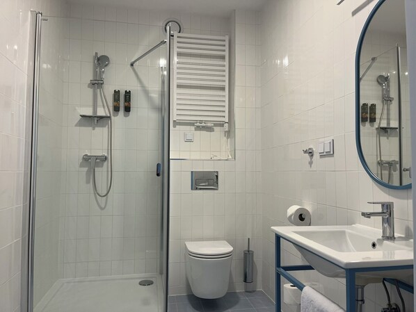 A modern bathroom with a glass-enclosed shower, a toilet, a sink, and a mirror. - Arche Metalowiec Muszyna (Muszyna)