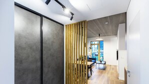 A modern interior with a sliding door, a wooden partition, and a view into a living area with a sofa and table.