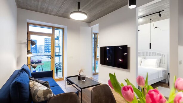 A modern living room with a sofa, coffee table, and a TV mounted on the wall.