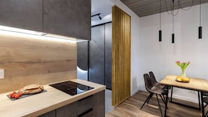 A modern kitchen with a built-in stove, wooden cabinets, and a dining area with a table and chairs.
