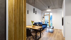 A modern living space with a dining area, a sofa, and a balcony with a view.