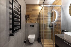 Ein modernes Badezimmer mit Duschkabine aus Glas, einer weißen Toilette und einem Waschbecken mit rundem Spiegel.