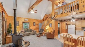 Interno di una baita in legno con un soggiorno, una cucina e un balcone.