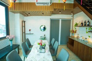 A dining area with a table, chairs, and a bar counter with bottles. - Atypik Vietnam House (Hanoi)
