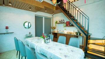 A dining area with a table set for four, a staircase, and a bar area with shelves.
