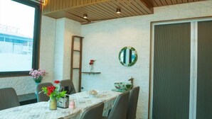 Un comedor con una mesa preparada para cuatro personas, un florero con flores y un espejo en la pared.