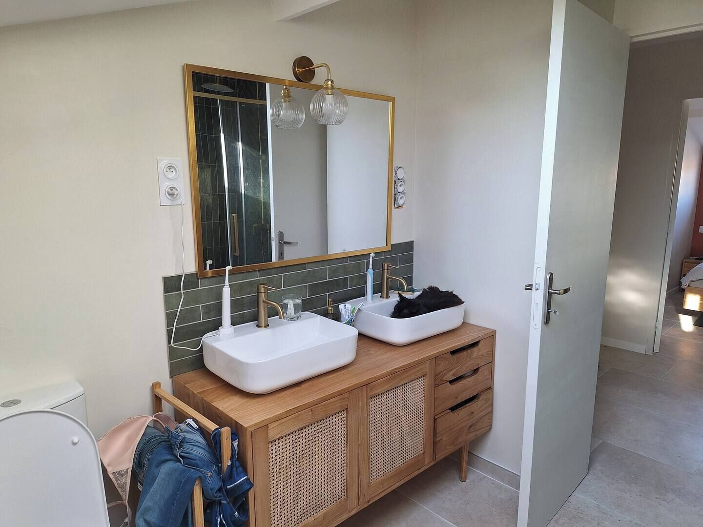 Une salle de bain avec un lavabo blanc, un miroir et un meuble-lavabo en bois.