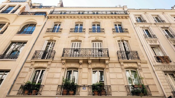Un edificio de varios pisos con balcones ornamentados, ventanas amplias y un estilo arquitectónico clásico.