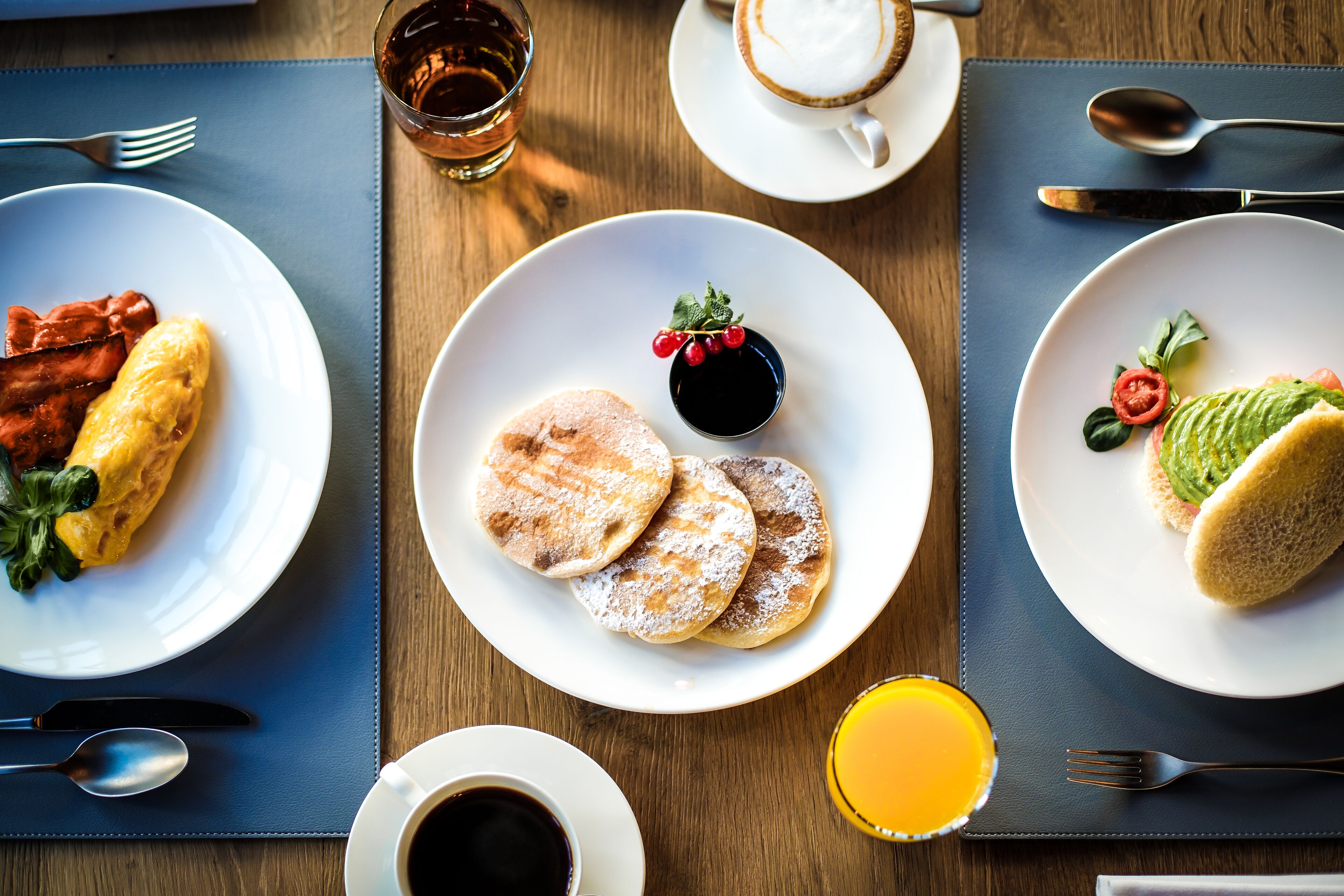 Ein gedeckter Frühstückstisch mit Speisen, einer Kaffeetasse und einem Glas Orangensaft.