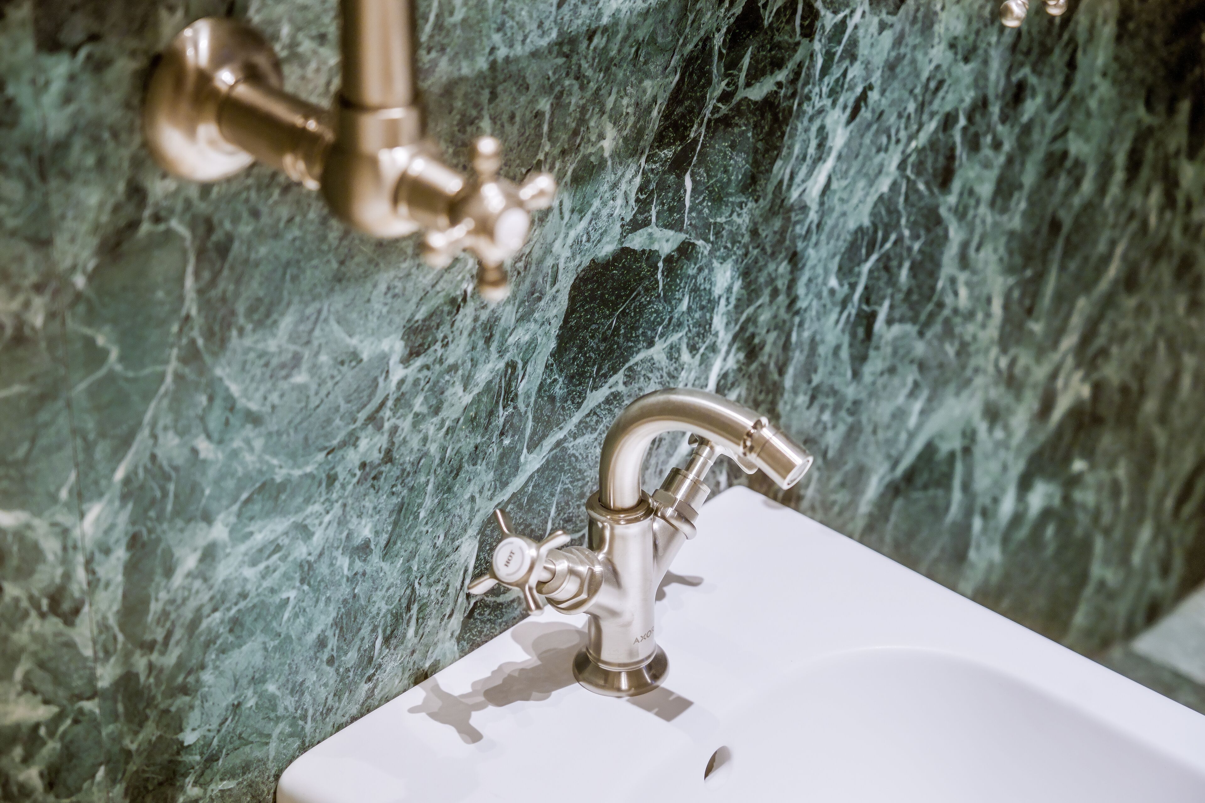 Un lavabo de salle de bain avec un robinet doré et un mur en marbre en arrière-plan.