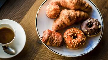 Um prato com croissants e um donut sobre uma mesa de madeira.