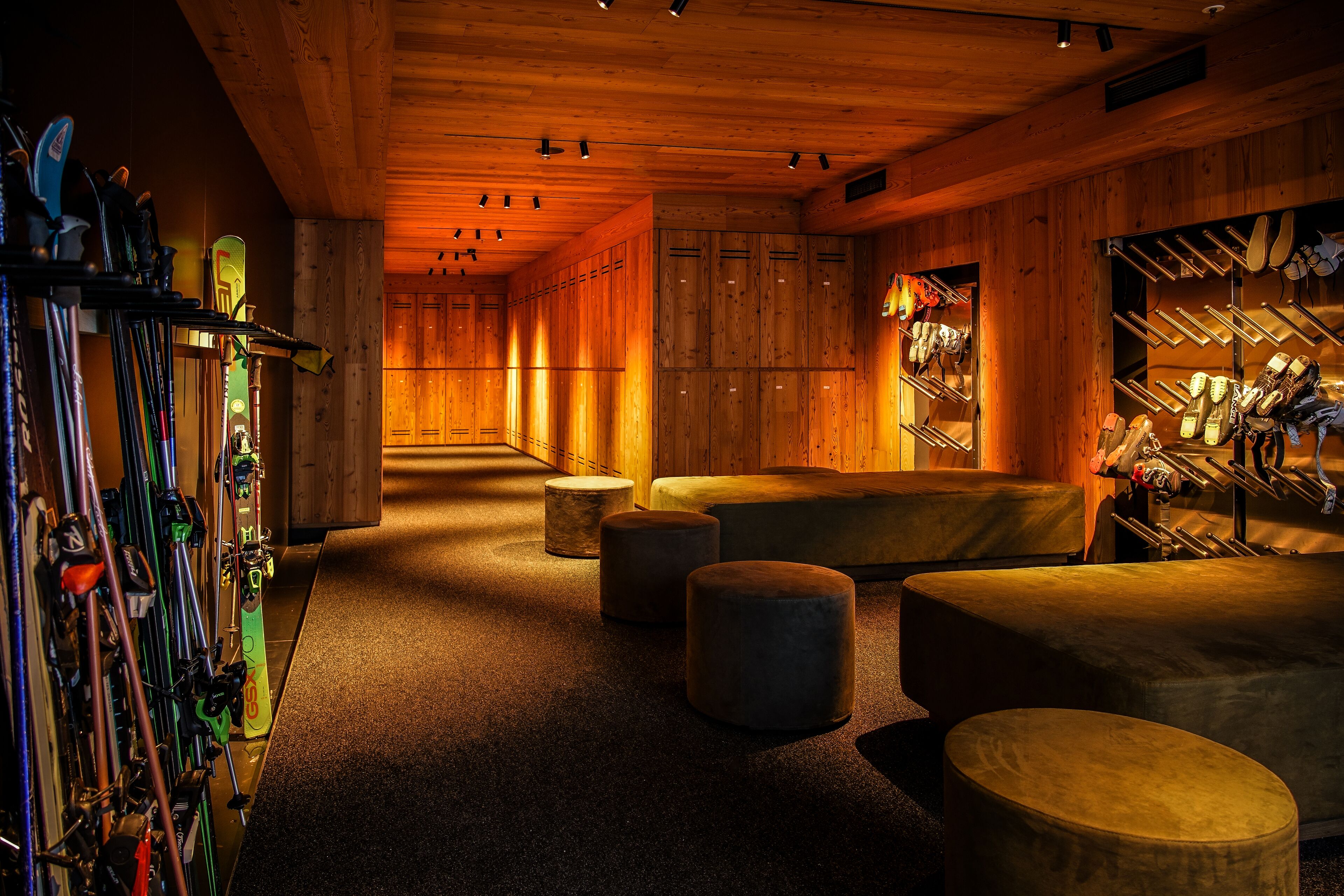 A ski lodge interior with wooden walls, a ski rack, and a seating area.