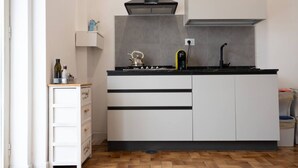 Uma cozinha compacta com fogão, chaleira e eletrodomésticos modernos.