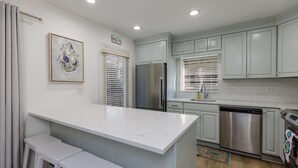 Una cocina moderna con muebles blancos, un refrigerador de acero inoxidable y un lavavajillas.
