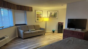 A cozy room with a sofa, a TV, a lamp, and a microwave. - Neat and Clean Rooms that are Affordable! (Hagerstown)
