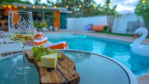 A glass of white wine, a wooden board with cheese and grapes, and a pool with a swan float. - Chic MangoTree villa/Heated Pool (Fort Lauderdale)