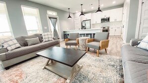 A modern living room with a sofa, armchairs, a coffee table, and a patterned rug. - Charming 3-bedroom, pet friendly, house in Crystal Beach. (Bolivar Peninsula)