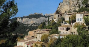 Un pueblo en la ladera con arquitectura tradicional, terreno rocoso y abundante vegetación.
