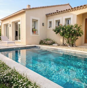 A swimming pool with clear water, a patio with lounge chairs, and a building with a tiled roof. - CASA-Vaison villa avec piscine privée (Vaison-la-Romaine)