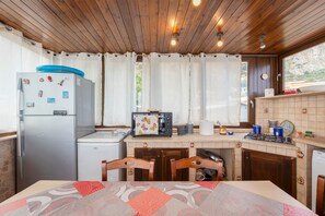 Une cuisine compacte équipée d’un réfrigérateur, d’un grille-pain et d’un évier. On y trouve également une table à manger avec des chaises.
