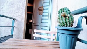 A wooden bench, a potted cactus, and a door with a sign in a room with a textured wall. - L'Isle Contemporaine - Spacious 74 M2 Clim Parking Downtown 2 bedrooms (L'Isle-sur-la-Sorgue)