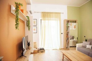 A living room with a TV, a bookshelf, a sofa, and a window with curtains. - Santa Cesira House in the Heart of Mentana (Mentana)