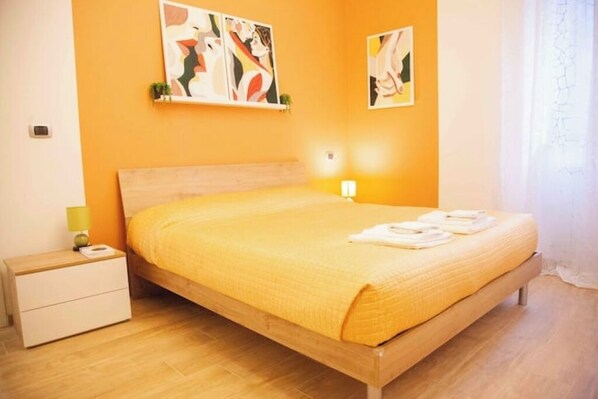 A bedroom with a wooden bed, a nightstand, and two wall-mounted paintings. - Santa Cesira House in the Heart of Mentana (Mentana)