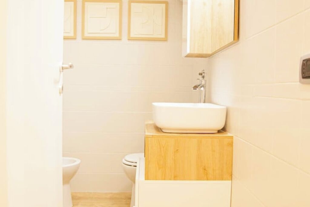 Une salle de bain avec un lavabo blanc, un meuble en bois et des toilettes.