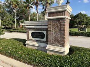 A sign with "CARRIAGE POINTE" on a brick structure with a decorative top. - Luxury Townhome on reunion resort (Kissimmee)