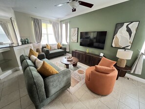 Een woonkamer met een bank, fauteuil, salontafel en een televisie.