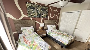 A bedroom with two beds, a ceiling fan, a door, and a wall with a giraffe print. - Luxury Townhome on reunion resort (Kissimmee)
