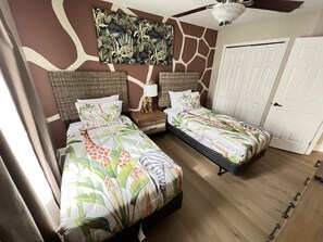 A bedroom with two beds, a ceiling fan, a door, and a wall with a giraffe print. - Luxury Townhome on reunion resort (Kissimmee)