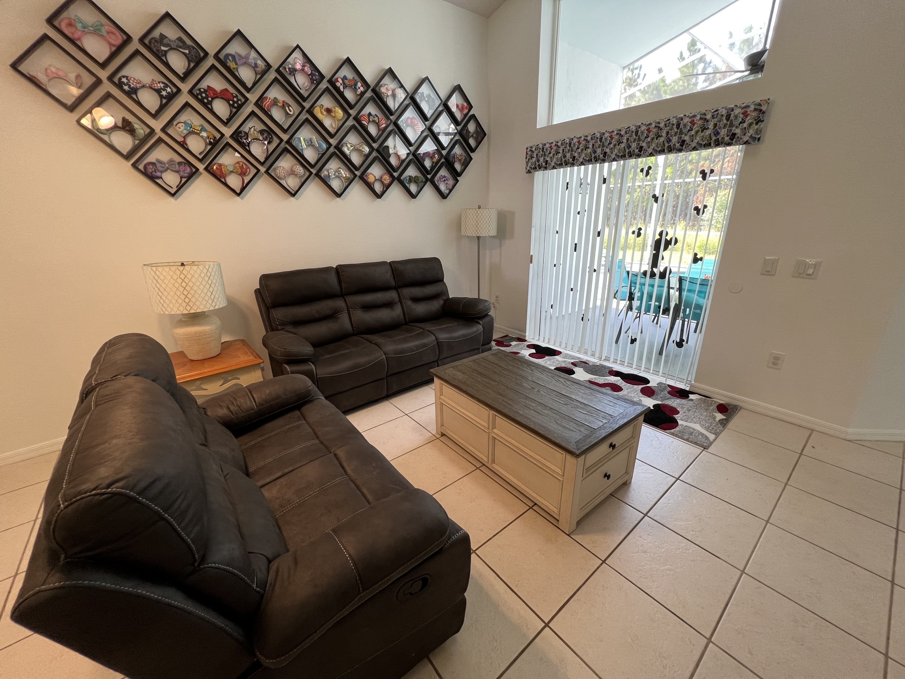 Ein Wohnzimmer mit einem Ecksofa, einem Couchtisch und einer Wand voller gerahmter Gegenstände.