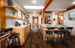 Una cocina con armarios de madera, una isla central con taburetes de bar y vistas al área de comedor.