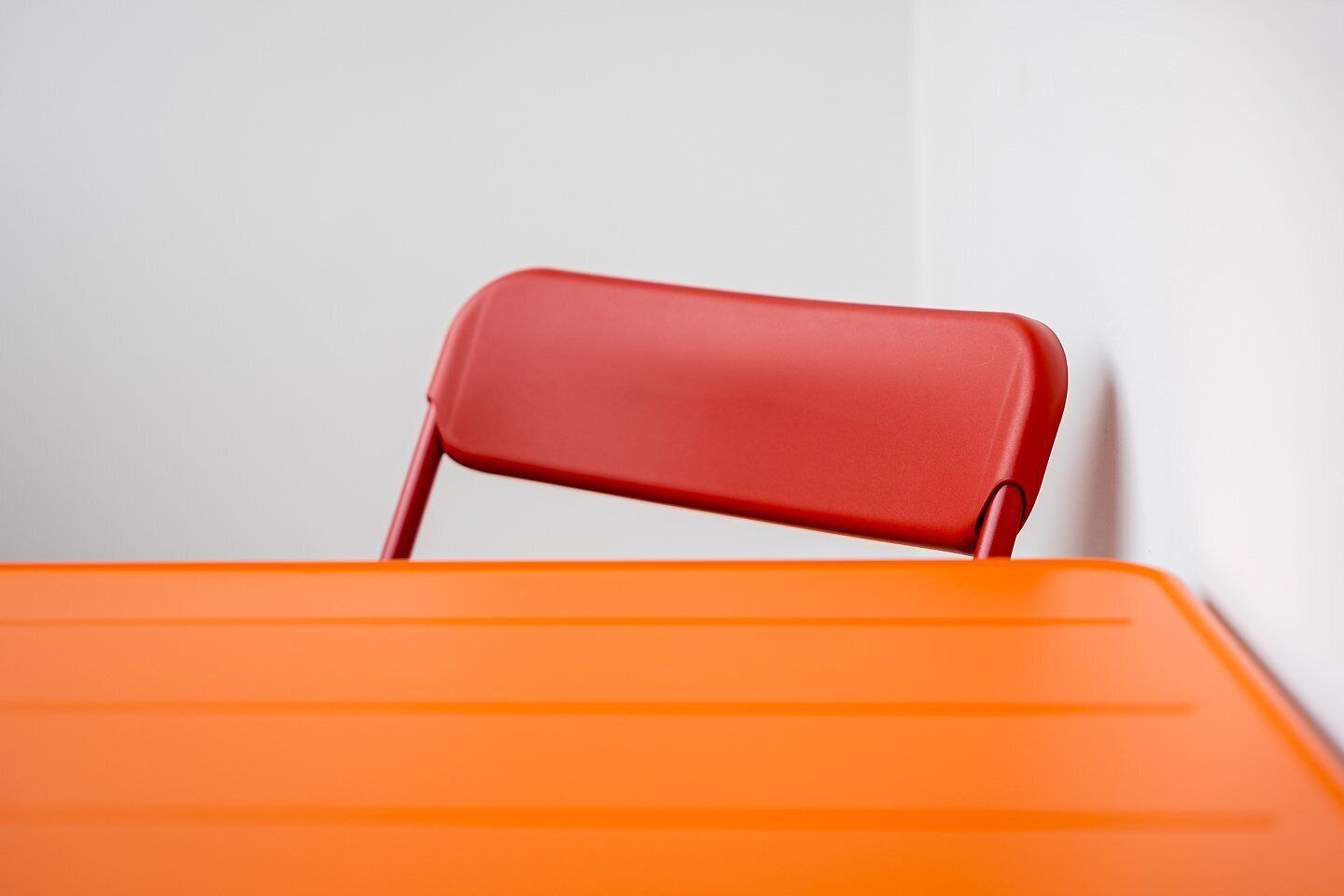 Ein roter Stuhl mit Lehne und ein orangefarbener Tisch.