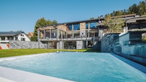 A modern two-story house with a swimming pool in the foreground.