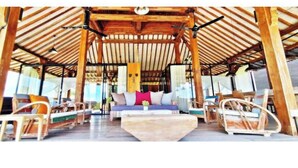 Un espacio al aire libre con techo, amueblado con madera y una mesa central.