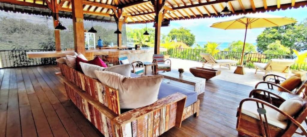 Eine Holzterrasse mit einer Sitzecke, einem Tisch und Blick auf das Meer.