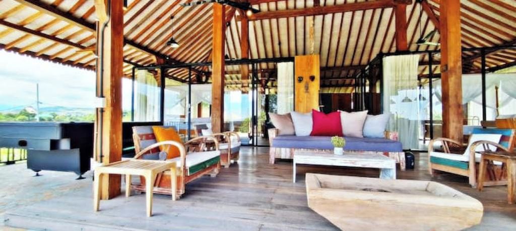 An open-air lounge with wooden furniture and a view of the landscape.