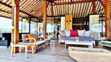 An open-air lounge with wooden furniture and a view of the landscape.