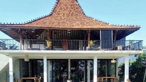 A building with a tiled roof, a swimming pool, and a covered outdoor seating area. - KAMAR MERAH. Comfortable 1BR Beachfront Apartment With AC, Pool & Kitchenette. (Tegallengah)
