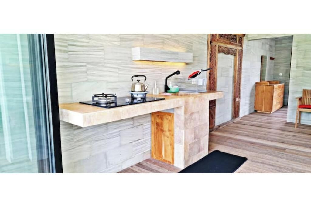 Una cocina moderna con salpicadero de mármol, estufa a gas, hervidor y cafetera.