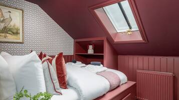 Quarto com teto inclinado, claraboia, radiador e cama com almofadas e cobertor.