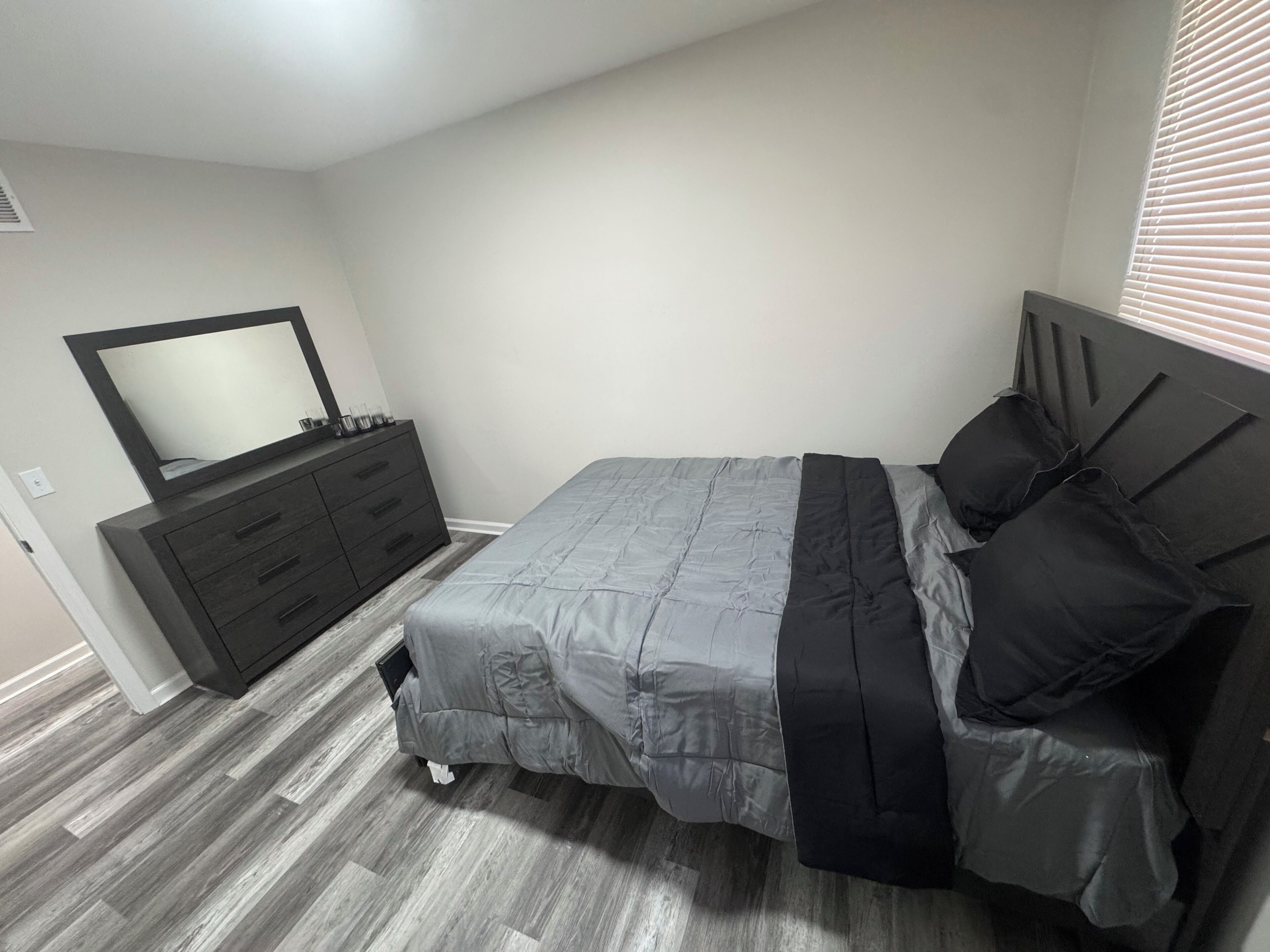Een slaapkamer met een bed, een dressoir en een spiegel.