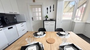 A modern kitchen with white cabinets, a black countertop, and a dining table set for four with glassware and plates. - The Dutt's cocoon: spacious and charming T3 (Duttlenheim)
