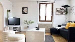 A modern living room with a flat-screen TV, a white coffee table, a black sofa, and a grey rug. - The Dutt's cocoon: spacious and charming T3 (Duttlenheim)