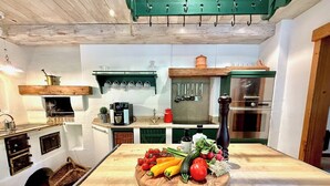 Una cocina con isla de madera, utensilios colgantes y una estufa.