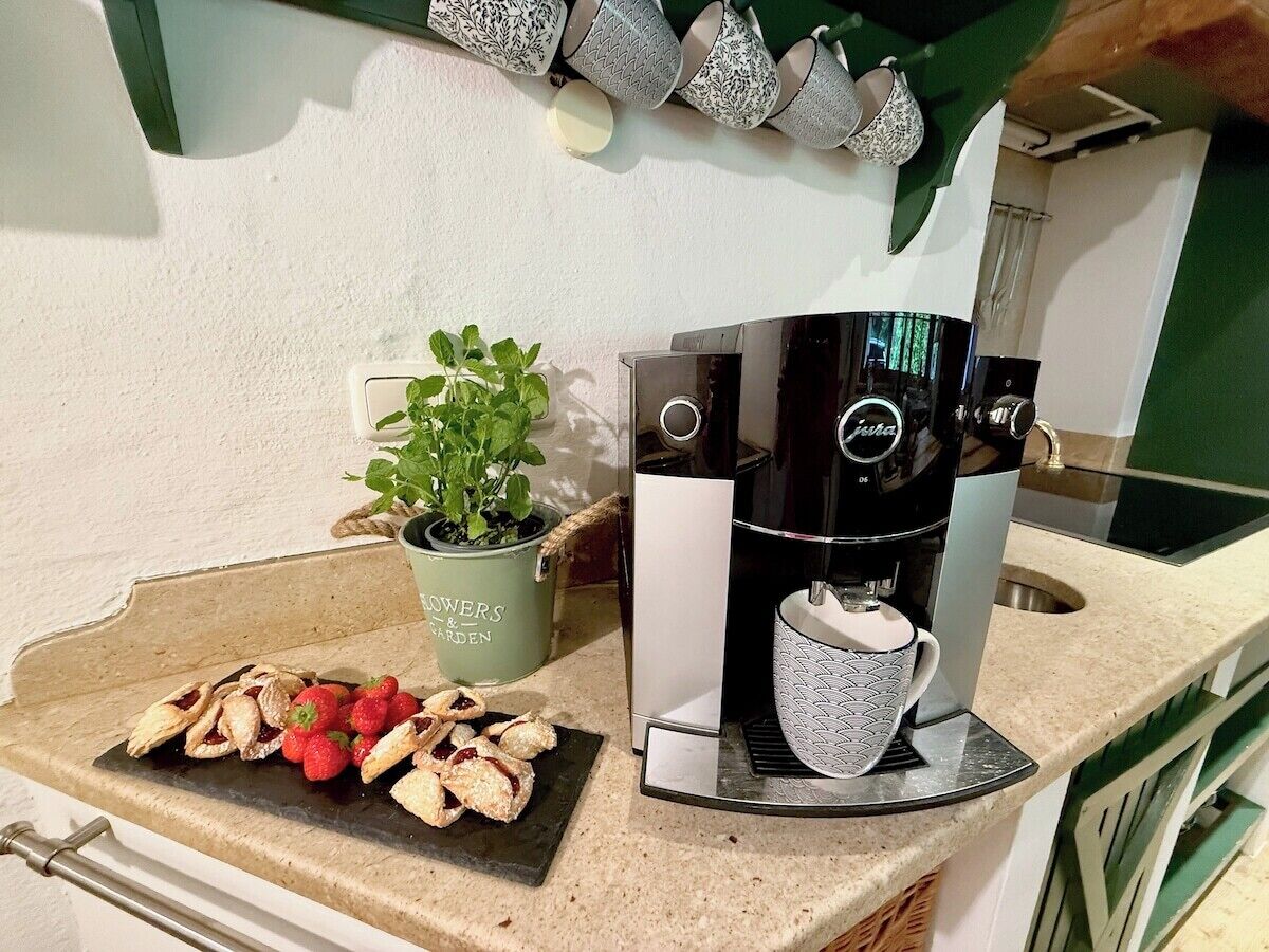Un piano di lavoro in cucina con una macchina da caffè, una pianta in vaso e un piatto di pasticcini.